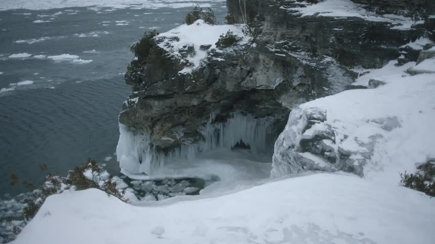 Snow is blowing off cliff tops on a coastline in winter