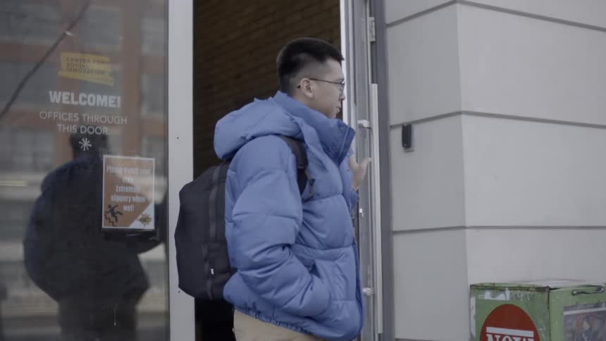 Man pushes open a glass door and exits a building