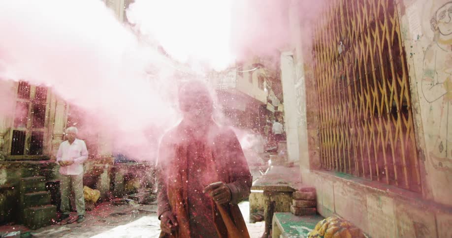Pink dust is thrown in an alleyway as a woman walks