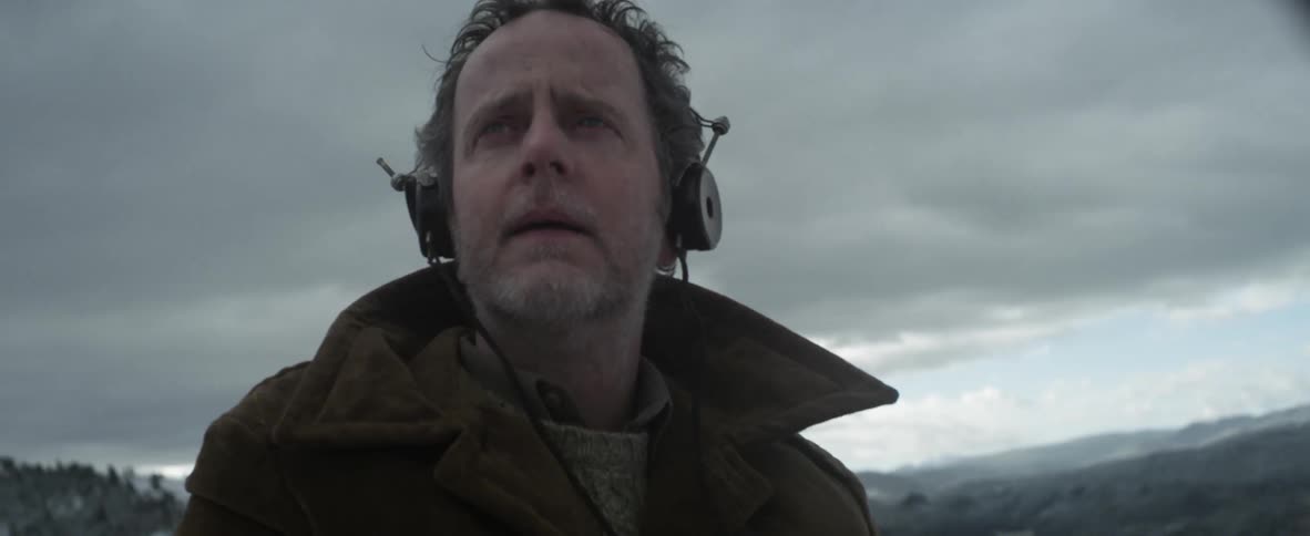 Man wearing headphones standing under a cloudy sky