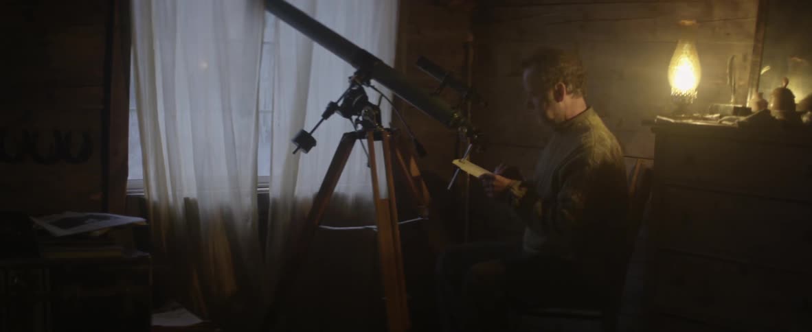 A man looking through and adjusting his telescope