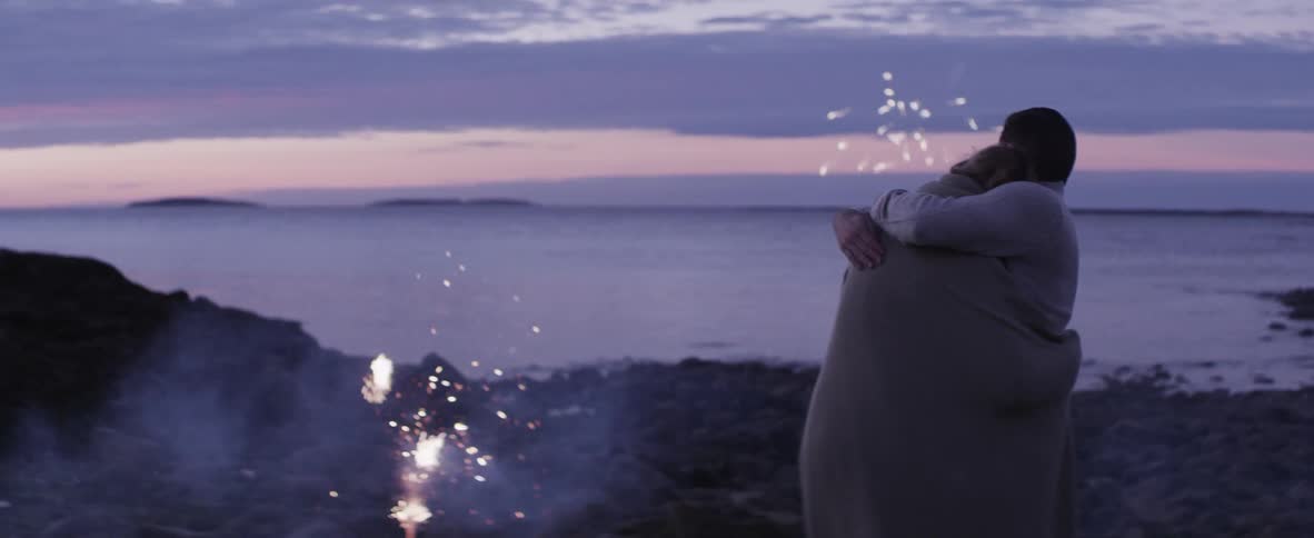 Two people hugging as they watch fireworks going off