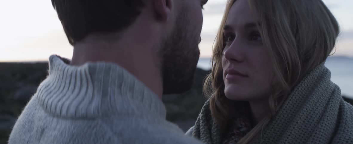 Woman wrapped in blanket stares at a man