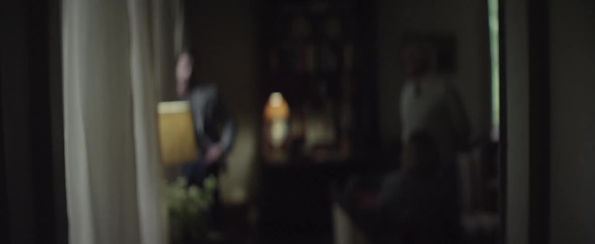 Woman almost enters room of people, leaves and is followed by a man