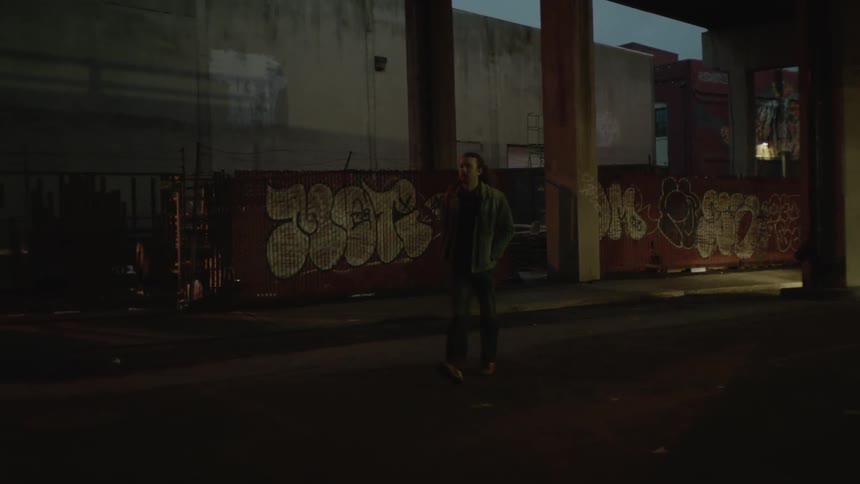 Man is walking down a dark city street at night