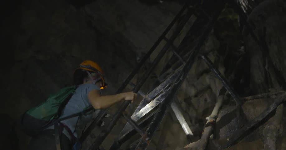 Woman climbs a ladder in a cave