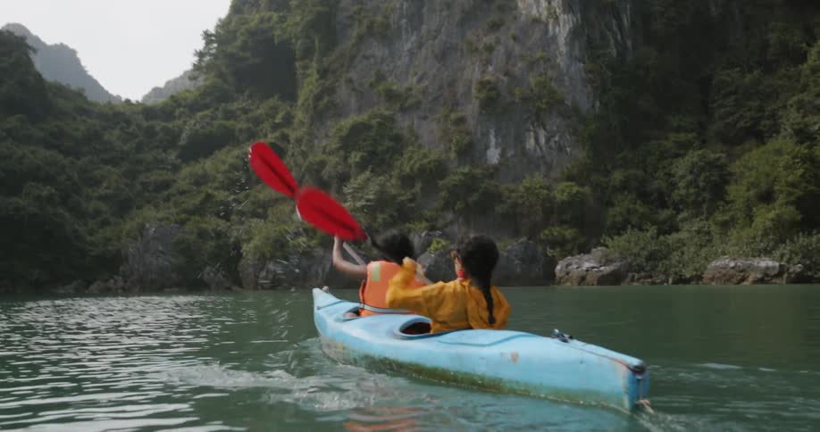 Two women paddle in a kayak in a river