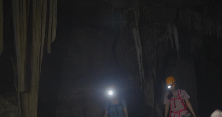 Woman wearing headlamps hike in a cave