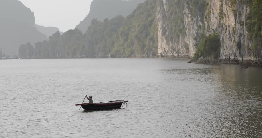 A person rows a boat and raises his other hand