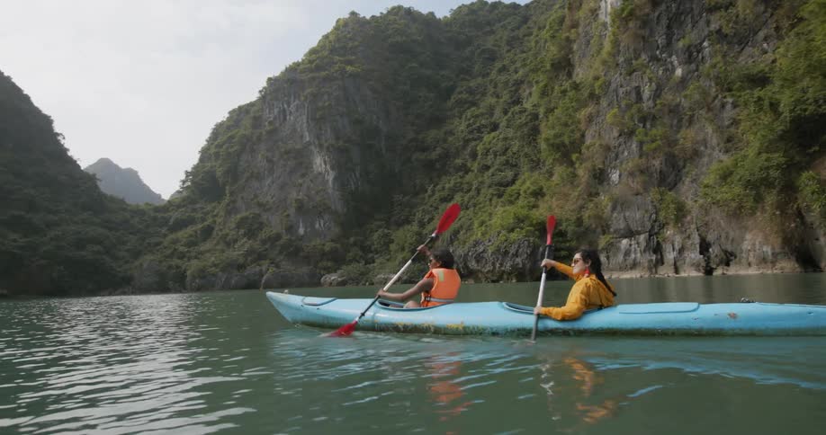 Two young women paddle a boat on the water