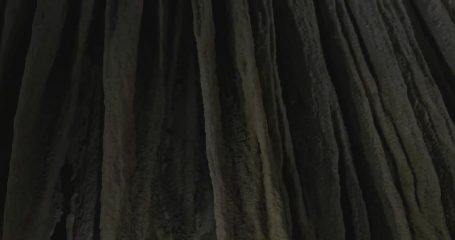 Stalactite hanging inside dark cave