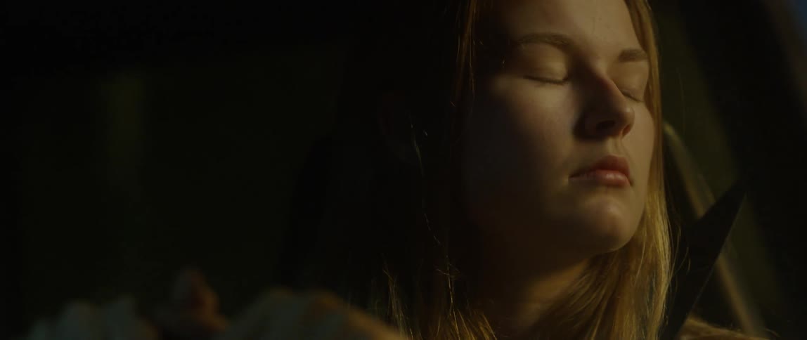 A woman looks towards the light in a vehicle