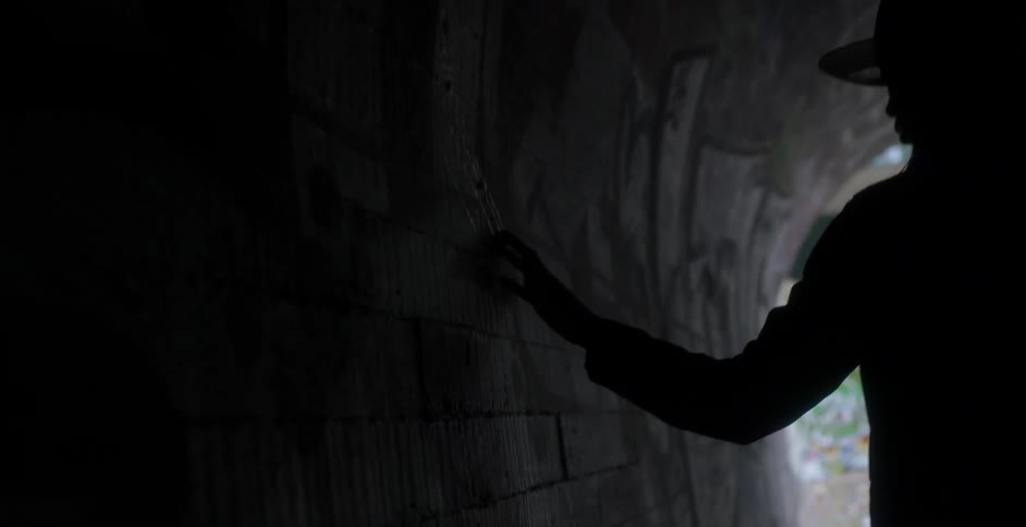 Woman touches the wall as she walks in a tunnel