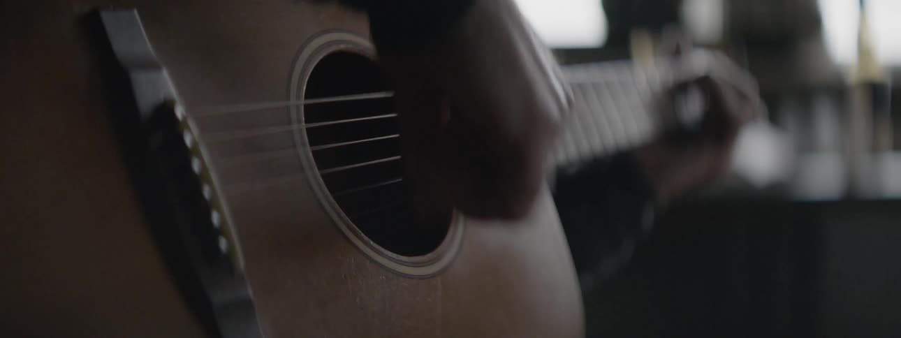 Man playing an acoustic guitar indoors