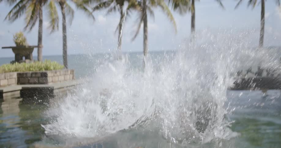 A man is cannonballing into a swimming pool on a sunny day