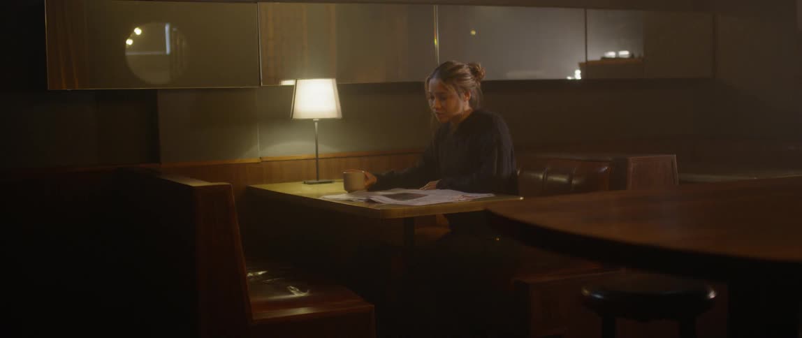 A woman sits alone in a restaurant booth