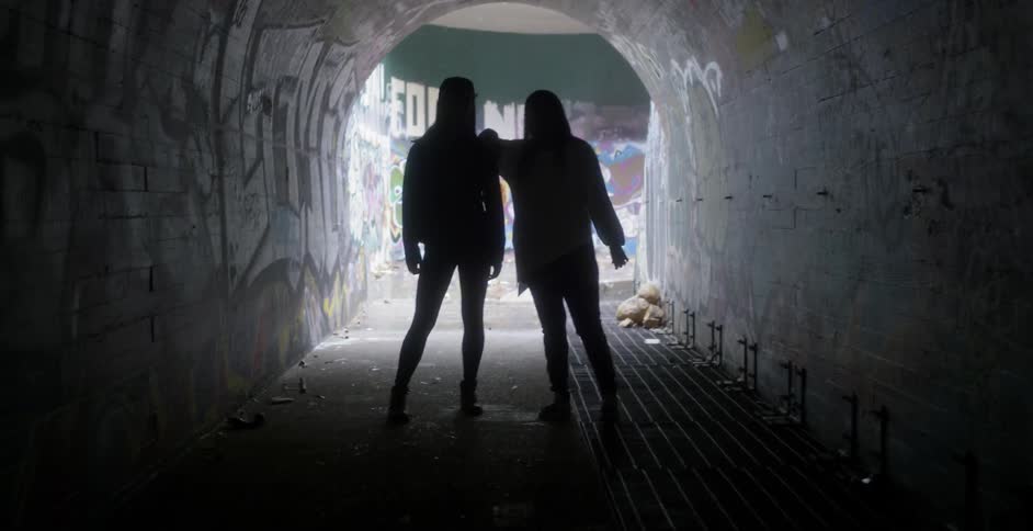 Two women stand in a tunnel
