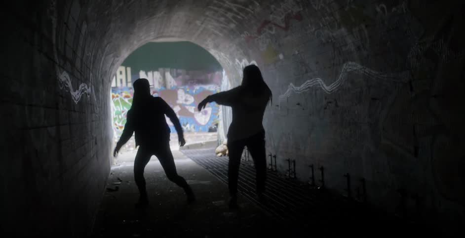 Two people dance in the tunnel in the dark