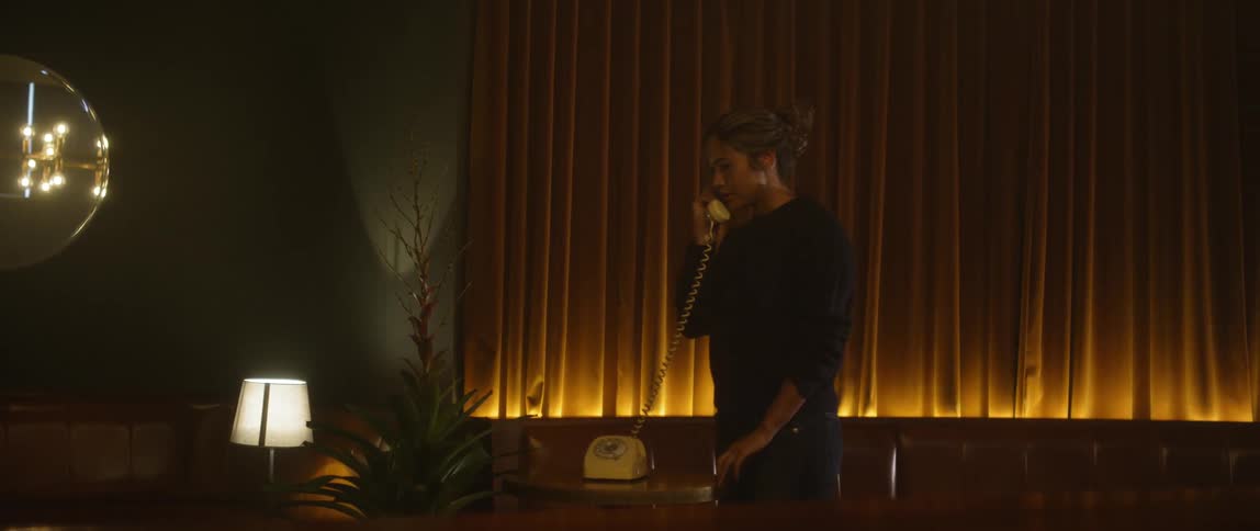 A woman uses a corded phone inside a restaurant