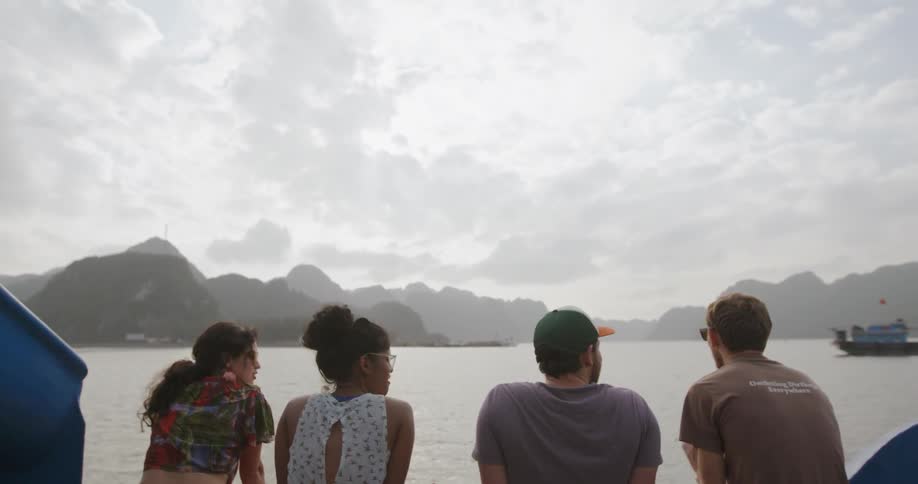 Group of people are talking while riding on boat on cloudy day