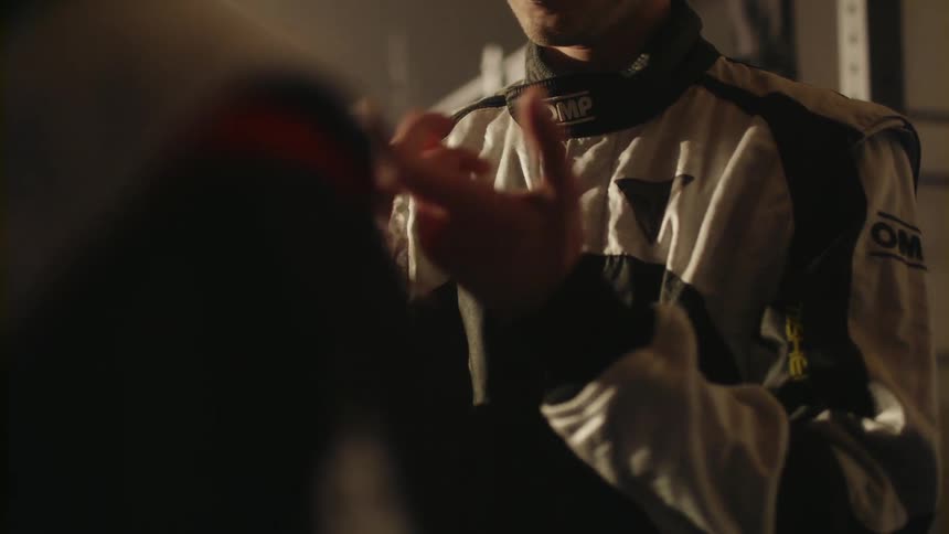 A man in a racing suit cracks his knuckles