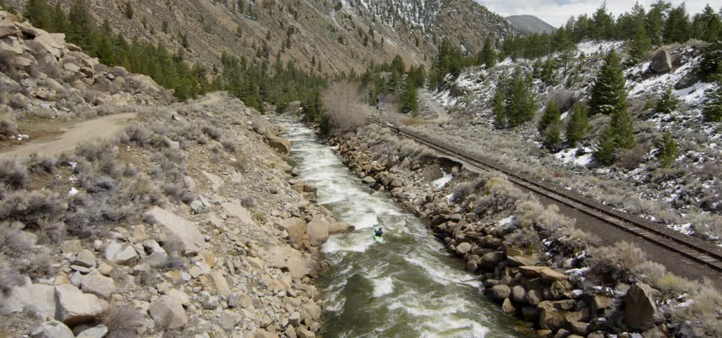 The stream is fast and pushing a person in a kayak