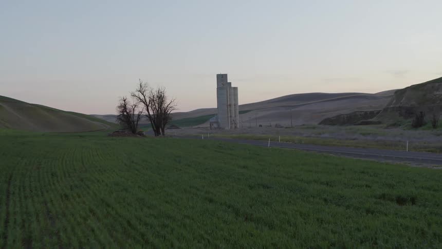 A pickup truck drives down a country road at sunset