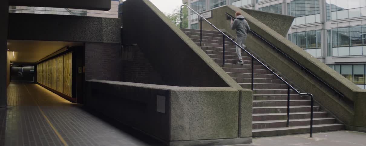 A man is jogging up a set of stairs outside in a city in daylight