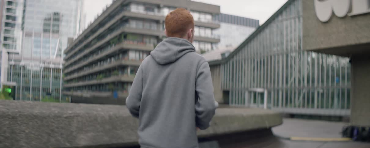 A man is jogging past the buildings on a cloudy day