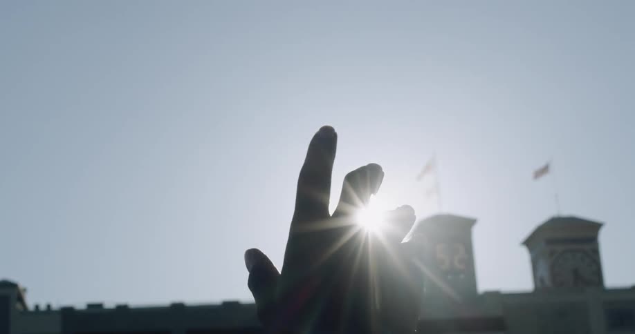 A person clenches their first over the sun in the sky