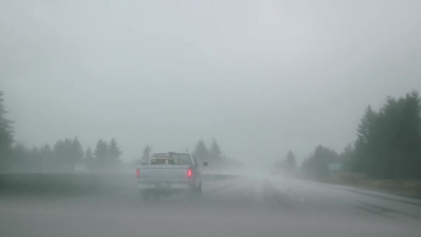 The car drives down the road in heavy rain