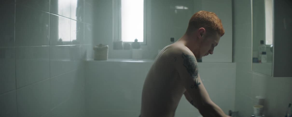 A man is leaning against the sink in his bathroom