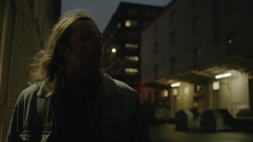 A man stands out on the street at dusk