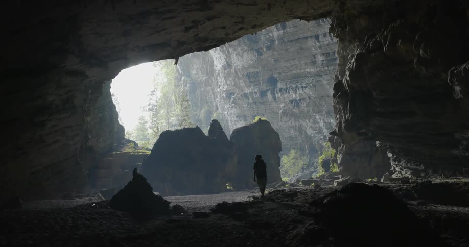 Man walks towards the opening in a cave