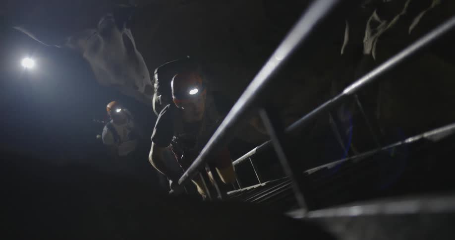 A person climbs steps out of a cavern at night