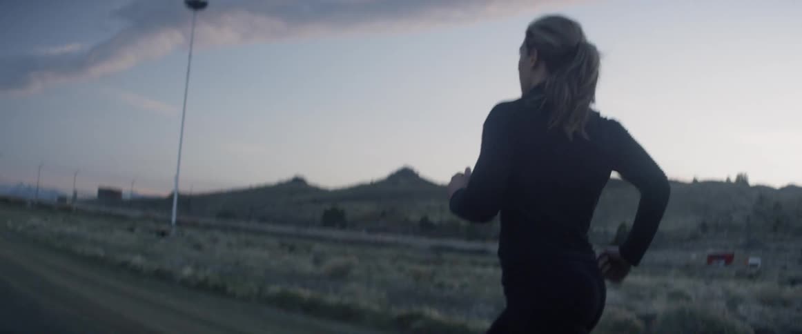 A woman jogs outside on the dirt