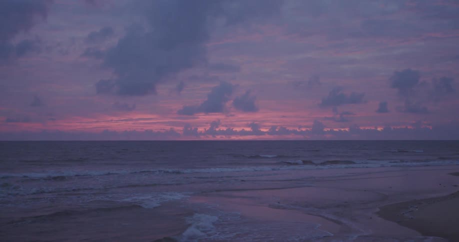 Ocean waves wash ashore a beach at sunset