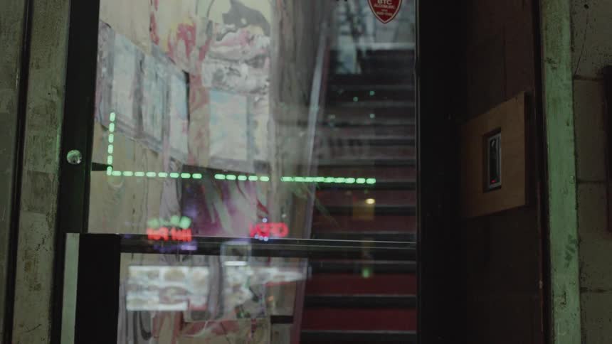 Lights from store fronts are reflected in the glass of a door