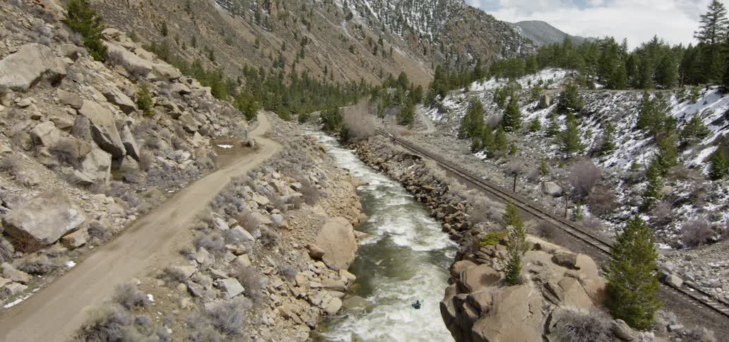 A person rides the rapids by the train tracks