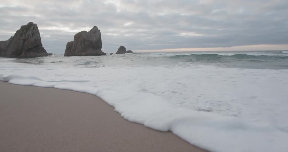Ocean waves wash ashore a beach at sunset