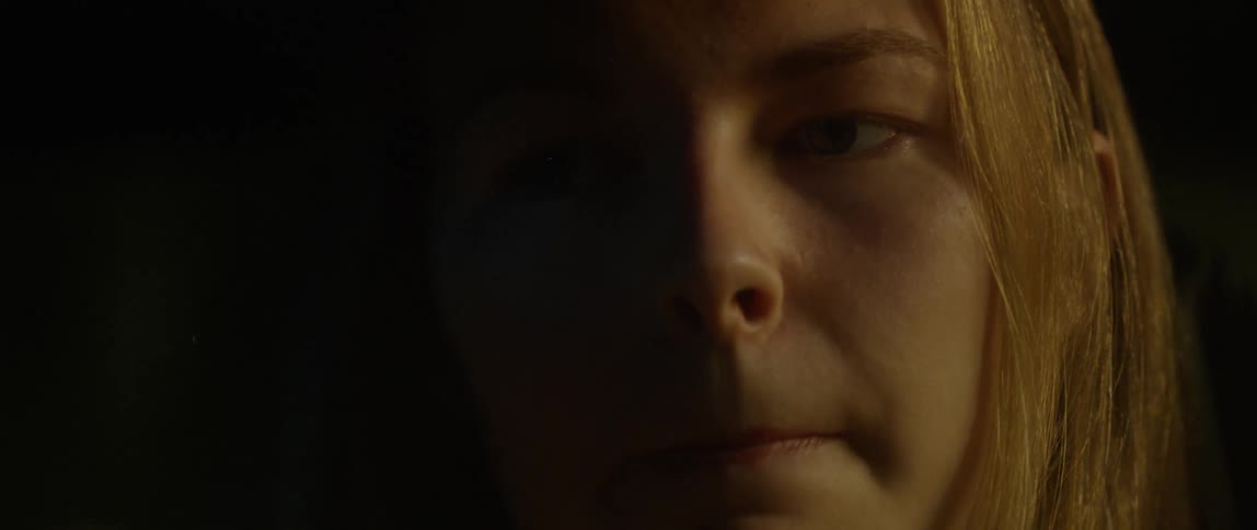 A woman looks to her side in the dark