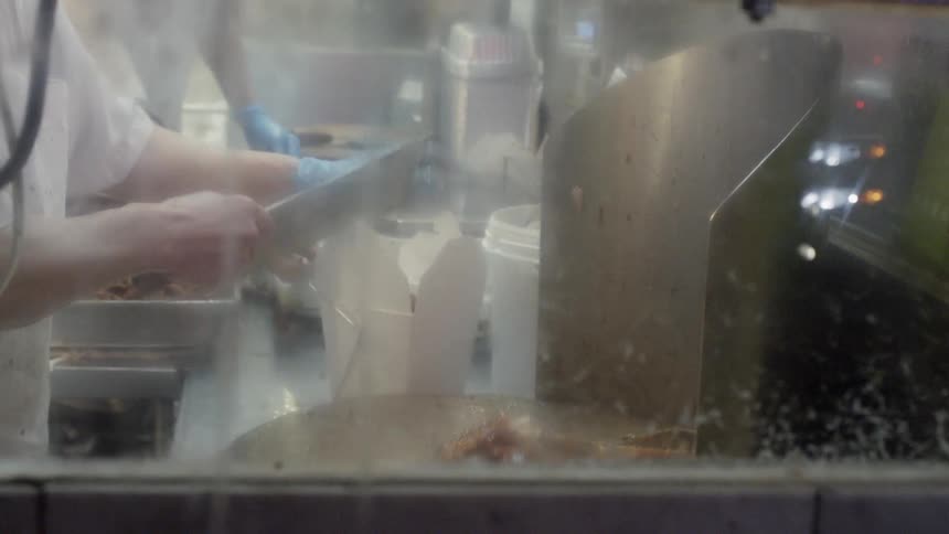 Cooked meat is chopped and added to a takeout container