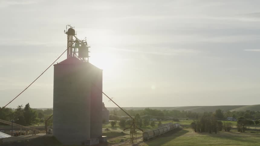 Pullback descent as the sun shines behind two large grain silos