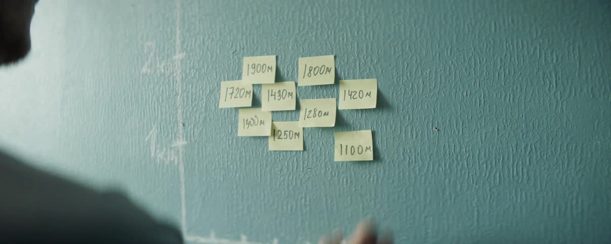 Yellow sticky notes are being stuck to a wall