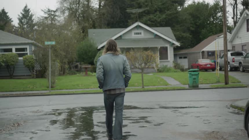 Man walks over the wet driveway towards the street
