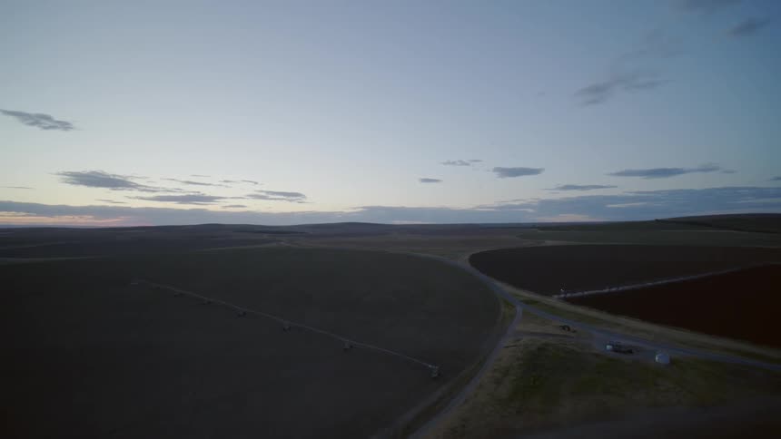 Clouds float over a rural farmland landscape at sunset