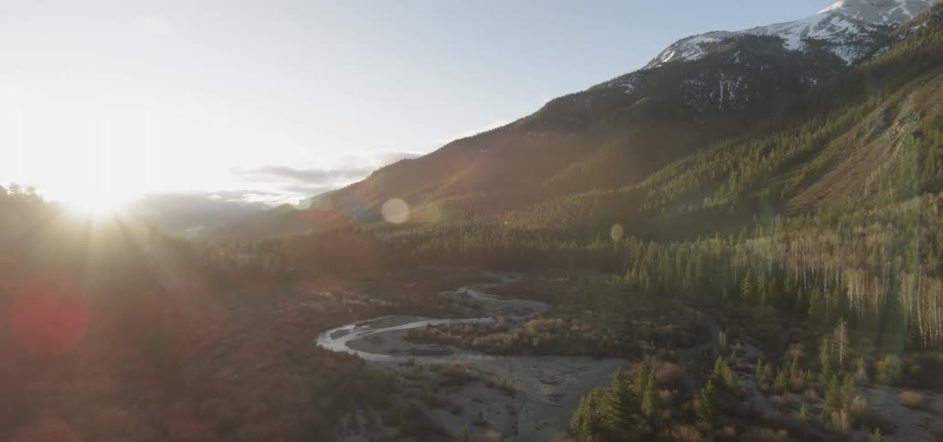 The sun shines on a valley below the mountain