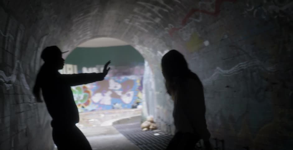 Two people dance in the dark tunnel