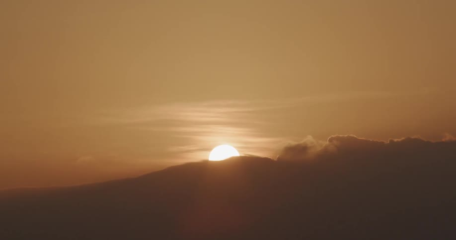 The sun is nearly set behind the mountain