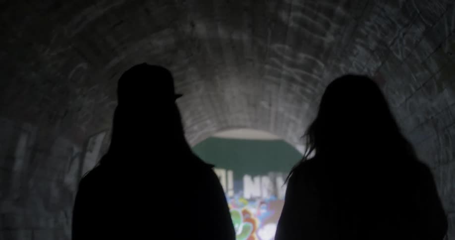 Two people walk out of the tunnel together